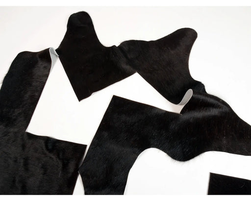 Black cowhide rug pieces with natural hair-on-hide texture for craft.