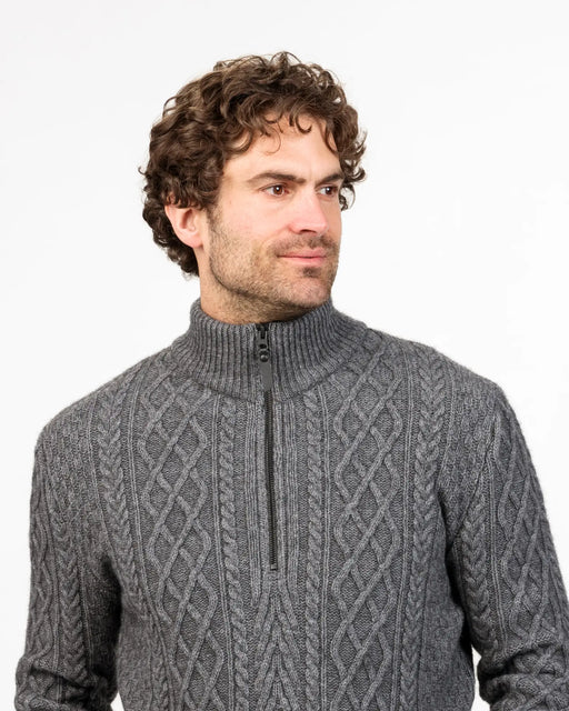 Man wearing a gray cable knit zip  sweater against a white background